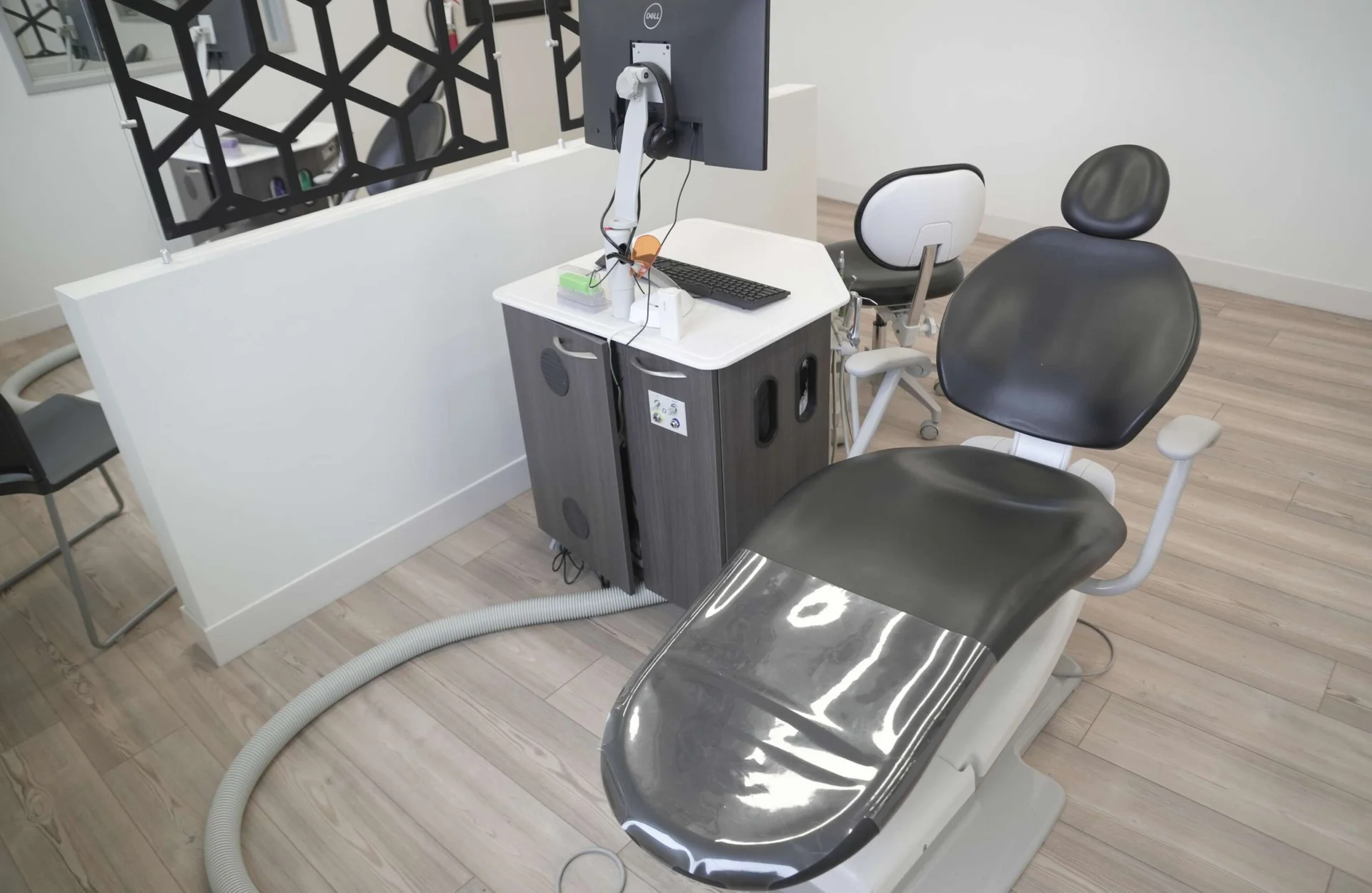 Modern orthodontic treatment chair beside a workstation with Dell monitor and dental tools